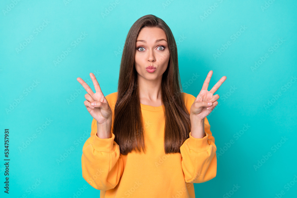 Photo of young attractive nice pretty woman wear orange sweater showing v-sign positive pouted lips cute hi everyone isolated on cyan color background Photo of young attractive nice pretty woman wear orange sweater showing v-sign positive pouted lips cute hi everyone isolated on cyan color background