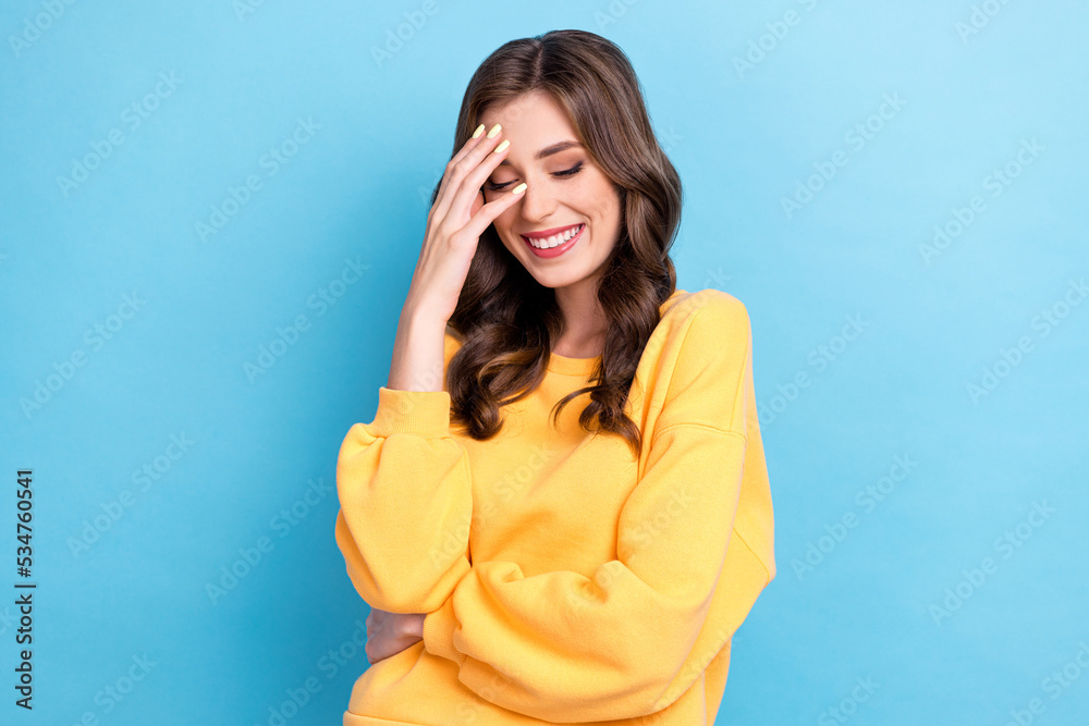 Closeup photo of young adorable dreamy pretty girlish lady toothy smile touch forehead wear yellow shirt curly hair isolated on blue color background Closeup photo of young adorable dreamy pretty girlish lady toothy smile touch forehead wear yellow shirt curly hair isolated on blue color background