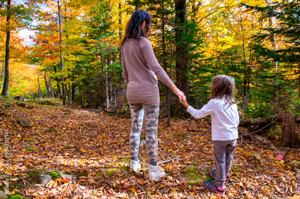 Happy mother and daughter walking along a trail in foliage season Happy mother and daughter walking along a trail in foliage season