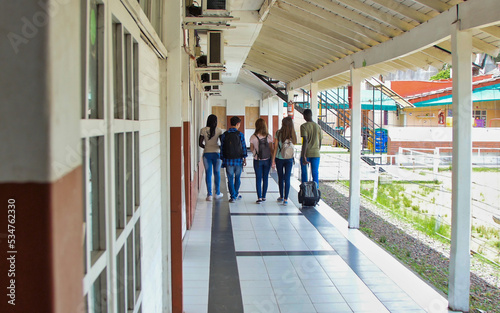Back view of multi ethnic schoolmates walking in the school hallway