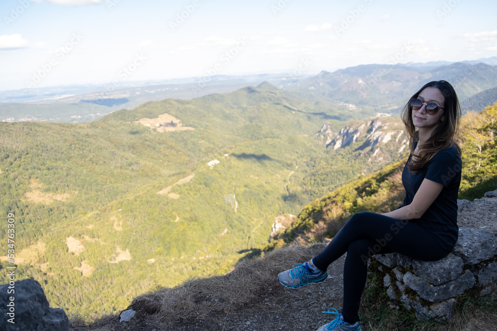 Young Woman with sunglasses seated at the top of the ruines of the Montsegur castle in France