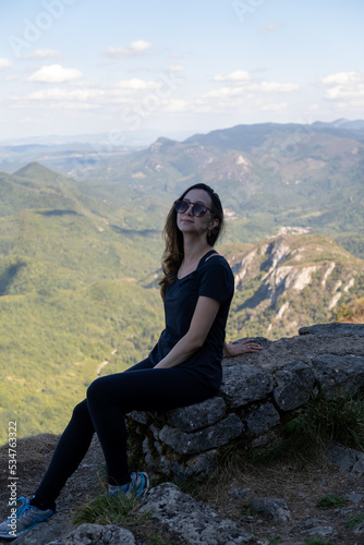 Young Woman with sunglasses seated at the top of the ruines of the Montsegur castle in France