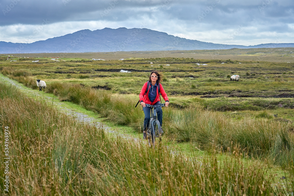 nice senior woman on mountain bike, cycling in the bog Area near Derrycunlagh, County Galway, in  the western part of the Republic of Ireland
