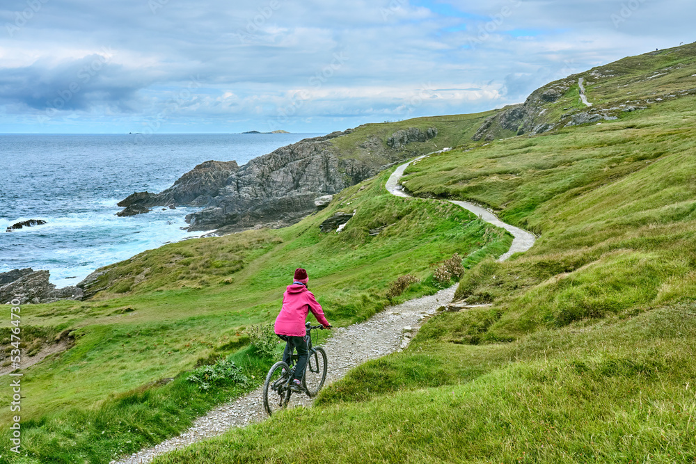 Fototapeta premium nice senior woman on mountain bike, cycling on the cliffs of Malin Head, the northern most point of Ireland