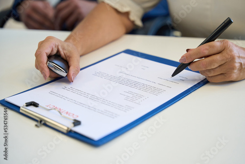Car dealership female signing documents at the office desk