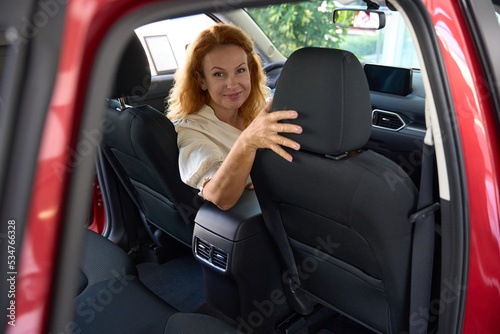 Beautiful woman sits in the driver's seat of car half-turned