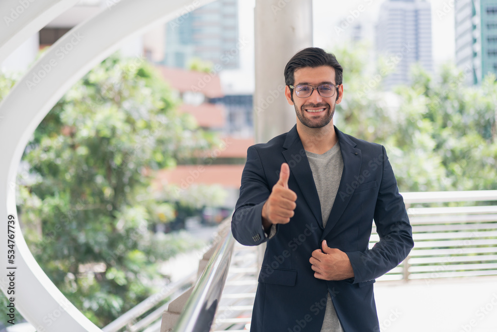 Happy businessman in black suit . young handsome business man doing happy thumbs up gesture with hand .