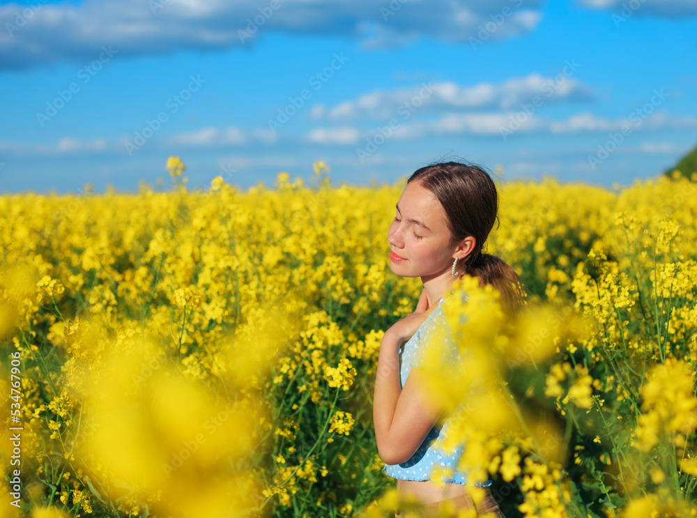 Beautiful teen girl is smiling with yellow flowers in summer field Beautiful teen girl is smiling with yellow flowers in summer field