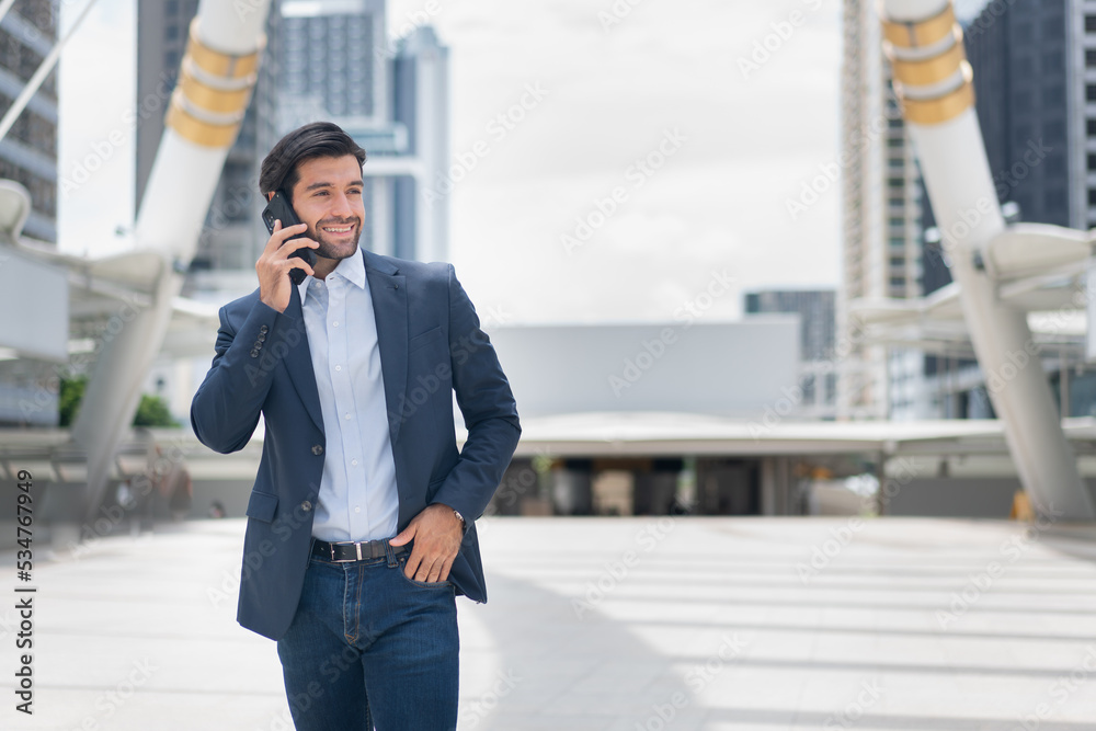 Urban business man talking on smart phone traveling walking at park . Casual young businessman wearing suit jacket . Handsome male model . Urban business man talking on smart phone traveling walking at park . Casual young businessman wearing suit jacket . Handsome male model .