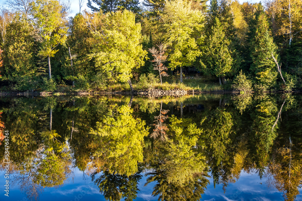 Fall colors in trees reflected on the still waters of the Madawaska River at Latchford Bridge Fall colors in trees reflected on the still waters of the Madawaska River at Latchford Bridge
