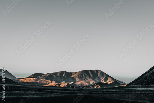 sad landscape of desert and lonely mountains under a gray sky without nature a car on the road at sunset, arthur pass, new zealand