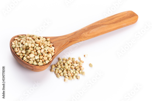 Raw buckwheat and wooden spoon on white background.