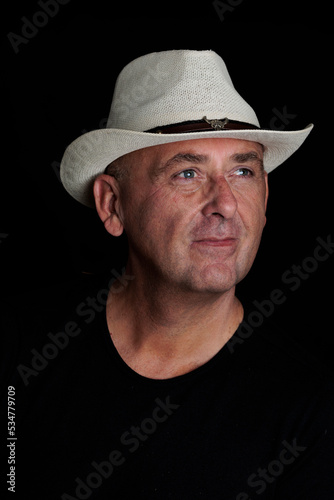 photography man over 50 years old with hat on black background