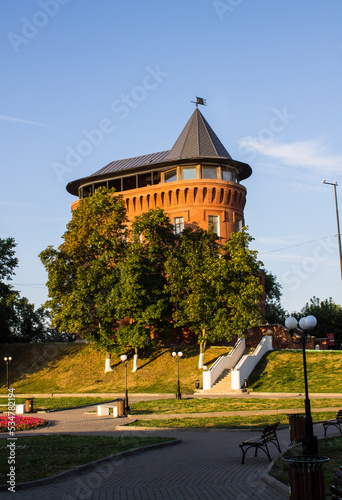 Vladimir, Russia, August, 17, 2022: An old brick water tower in the historical center of the city among green trees on a sunny summer day