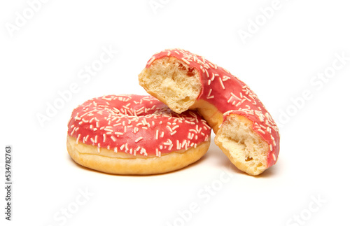 Whole and bitten donuts with frosted pink color glaze and white sprinkles isolated on white background