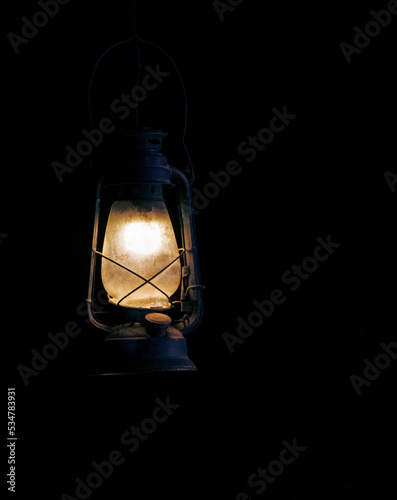 Vintage weathered lamp, dimly lit in the darkness ,isolated background.