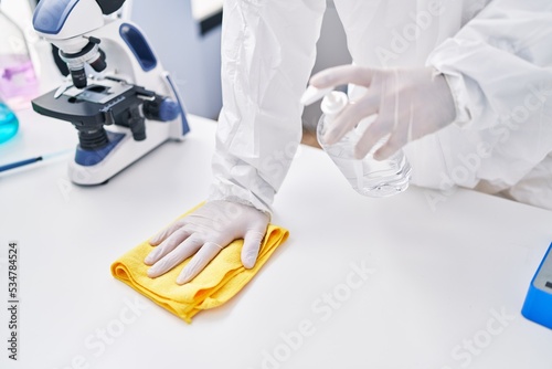 Young hispanic man scientist cleaning table at laboratory