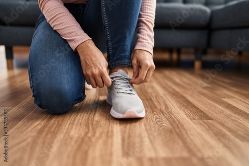 Young woman tying shoelace at home photo