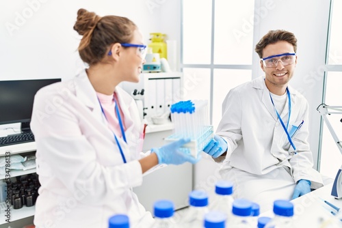 Man and woman wearing scientist uniform holding test tube at laboratory