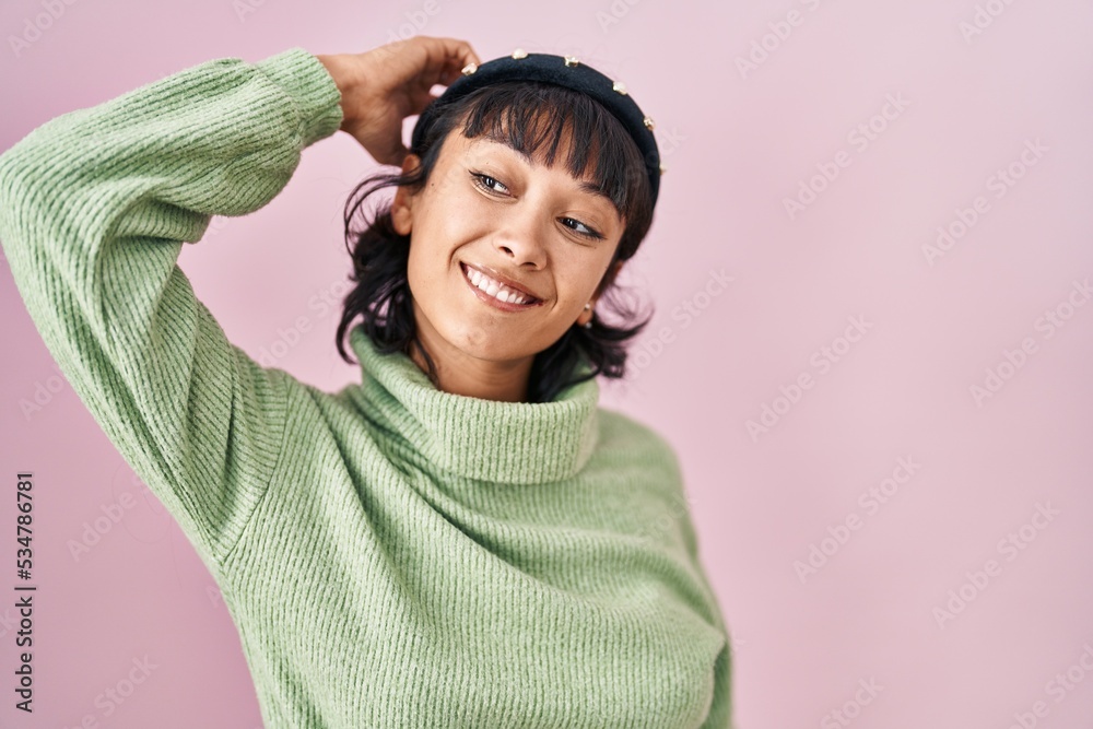 Young beautiful woman standing over pink background smiling confident touching hair with hand up gesture, posing attractive and fashionable Young beautiful woman standing over pink background smiling confident touching hair with hand up gesture, posing attractive and fashionable
