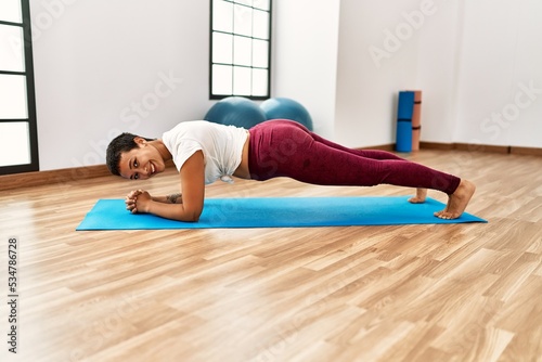 Young hispanic woman smiling confident training abs exercise at sport center