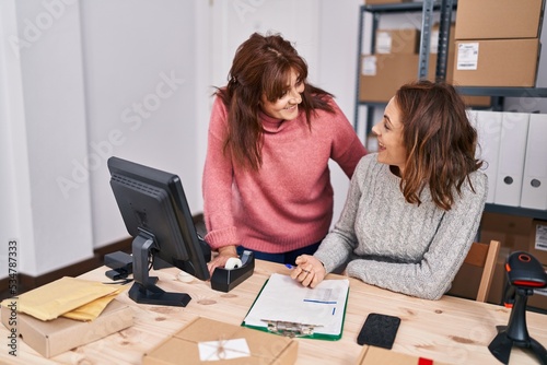 Two women ecommerce business workers writing on document at office