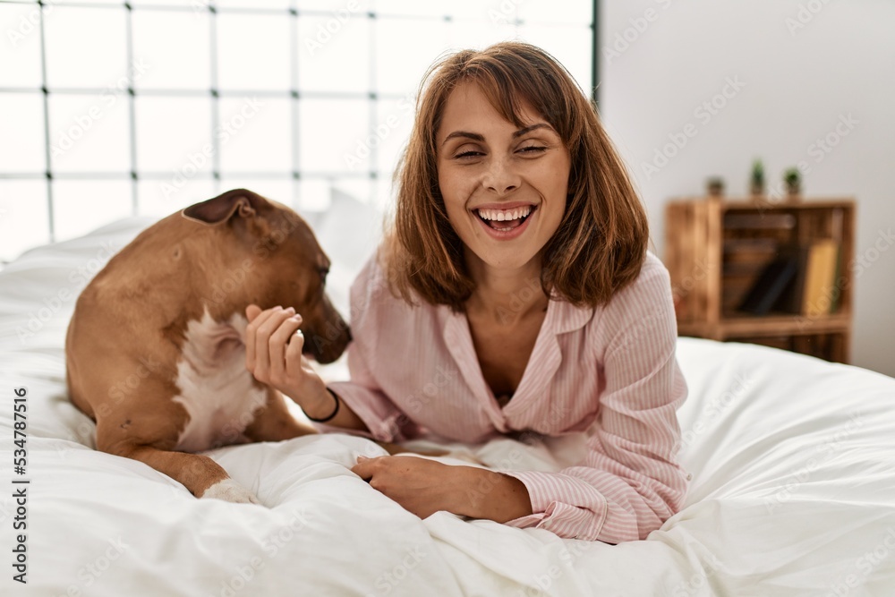 Young caucasian woman smiling confident lying on bed with dog at bedroom Young caucasian woman smiling confident lying on bed with dog at bedroom