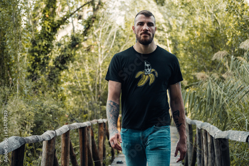 Young man in a casual outfit walking on a wooden walkway in a forest