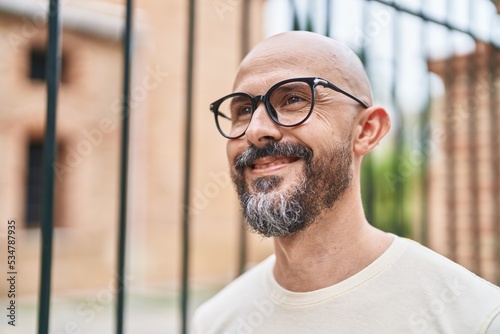 Young bald man smiling confident wearing glasses at street © Krakenimages.com