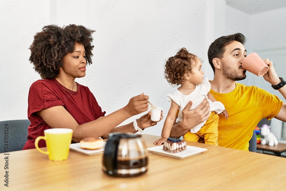 Couple and daughter having breakfast sitting on table at home Couple and daughter having breakfast sitting on table at home