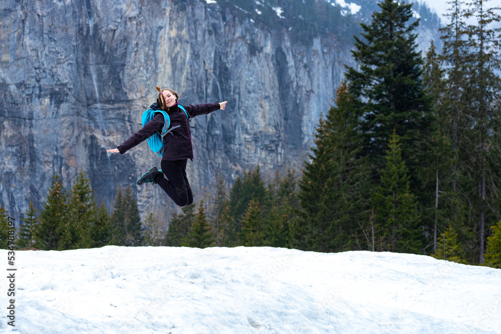 sweet woman in pigtails jumps for joy during a mountain hike in snowy mountains; mountain climbing in the alps, lake oeschinen