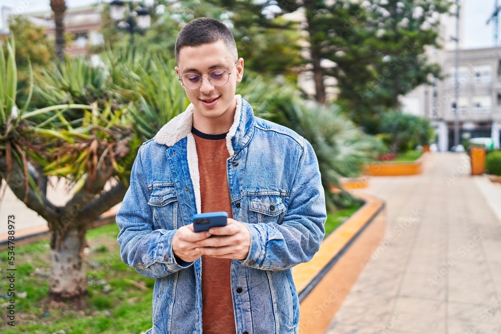 Fototapeta premium Young hispanic man smiling confident using smartphone at park