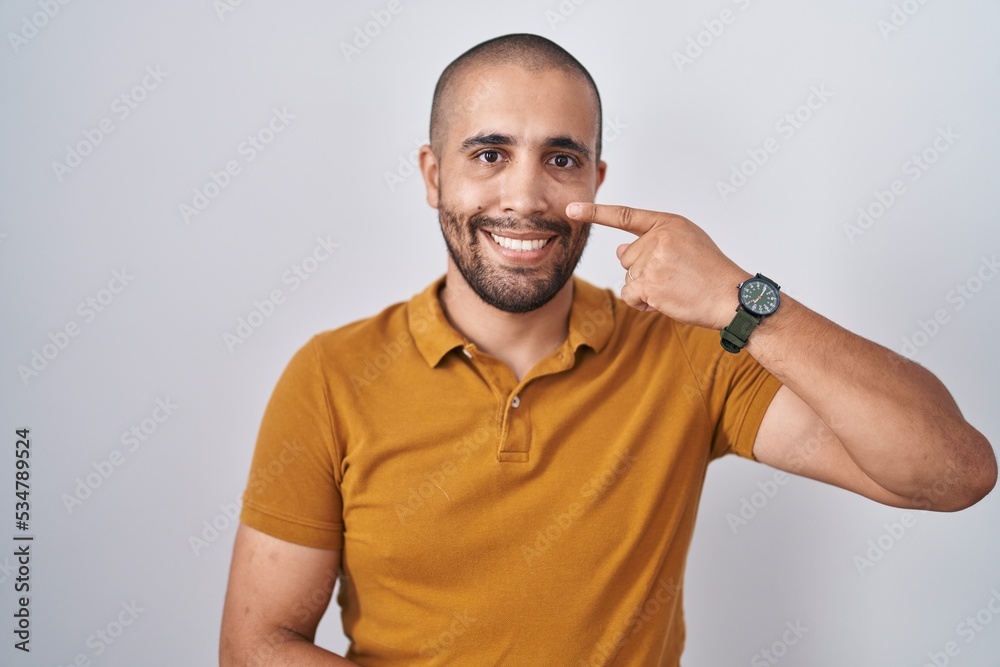 Hispanic man with beard standing over white background pointing with hand finger to face and nose, smiling cheerful. beauty concept Hispanic man with beard standing over white background pointing with hand finger to face and nose, smiling cheerful. beauty concept
