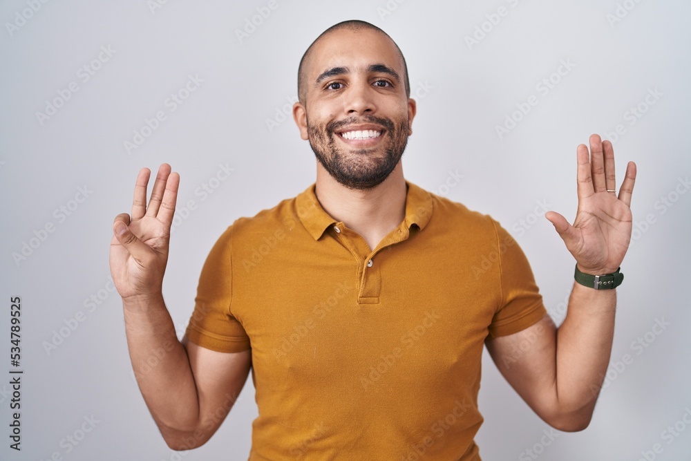 Hispanic man with beard standing over white background showing and pointing up with fingers number eight while smiling confident and happy. Hispanic man with beard standing over white background showing and pointing up with fingers number eight while smiling confident and happy.