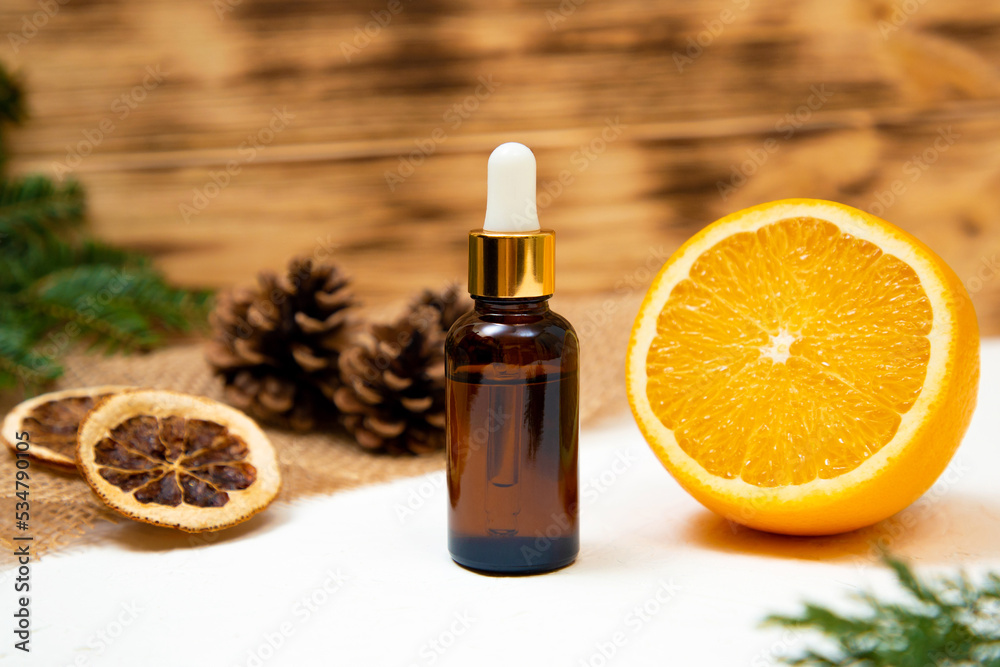 essential oil on a wooden background with orange and pine cones