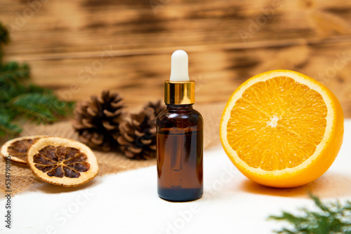 essential oil on a wooden background with orange and pine cones