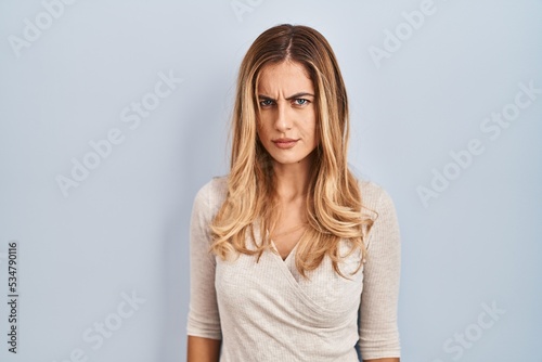 Young blonde woman standing over isolated background skeptic and nervous, frowning upset because of problem. negative person.