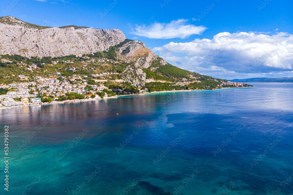 aerial view of the town of omiš in croatia, a picturesque town on the adriatic coast with the mouth of the cetina river, a beautiful beach and mighty mountains in the background as seen from a drone