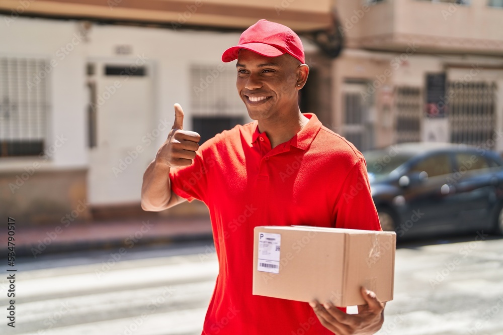 Young latin man delivery worker holding package doig ok gesture with finger at street Young latin man delivery worker holding package doig ok gesture with finger at street