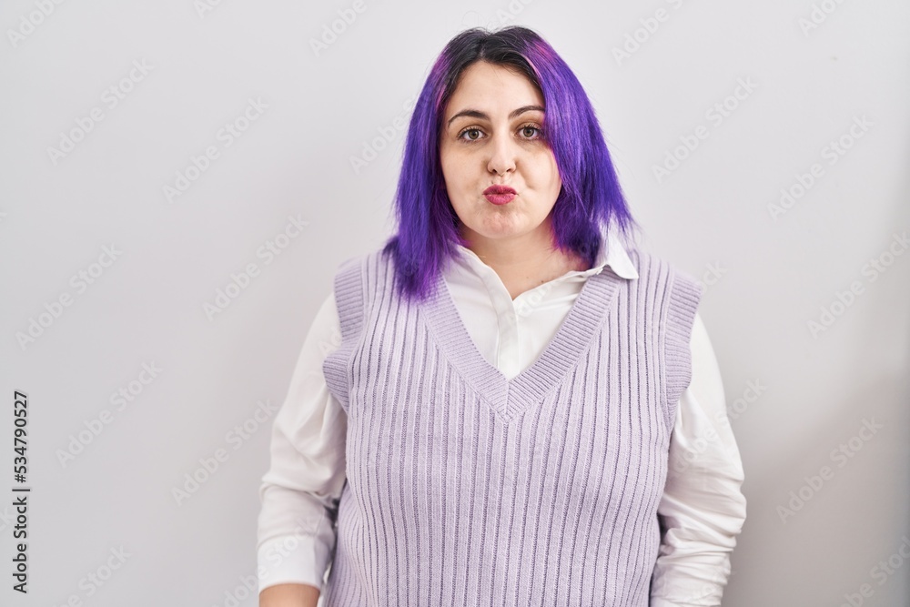 Plus size woman wit purple hair standing over white background looking at the camera blowing a kiss on air being lovely and sexy. love expression. Plus size woman wit purple hair standing over white background looking at the camera blowing a kiss on air being lovely and sexy. love expression.