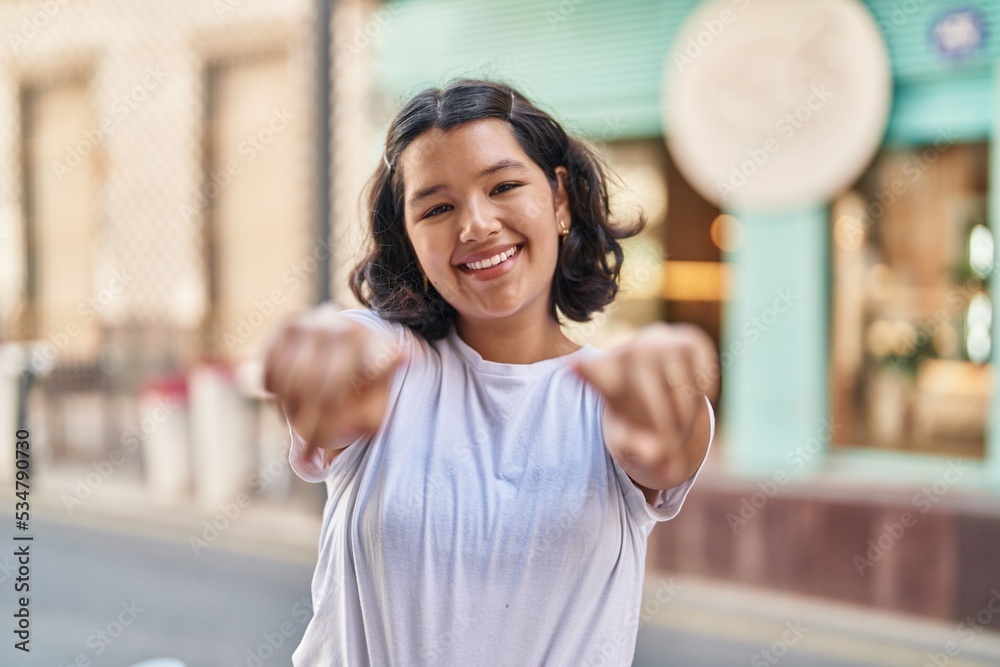 Young woman smiling confident pointing with fingers at street Young woman smiling confident pointing with fingers at street