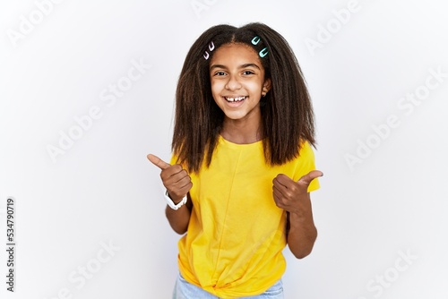 Young african american girl standing over white isolated background success sign doing positive gesture with hand, thumbs up smiling and happy. cheerful expression and winner gesture.