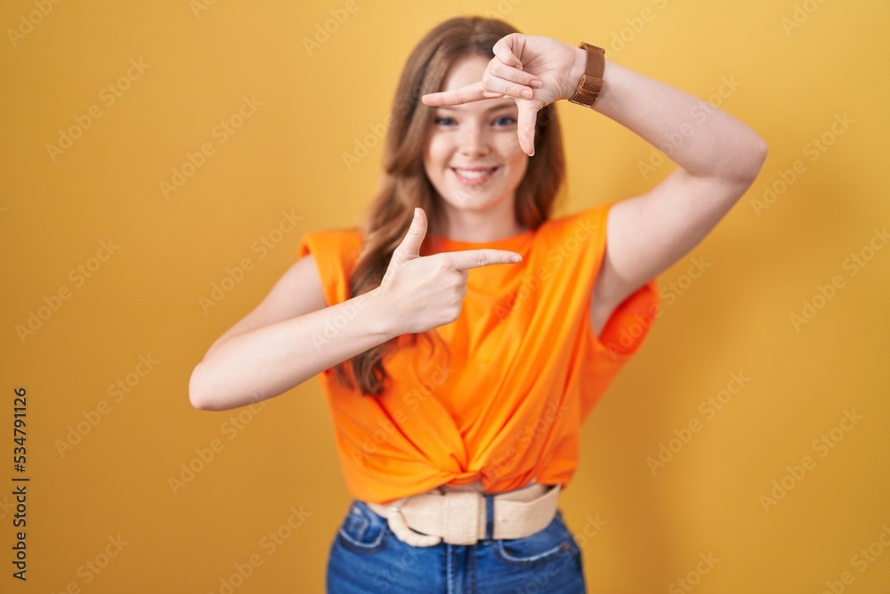 Caucasian woman standing over yellow background smiling making frame with hands and fingers with happy face. creativity and photography concept. Caucasian woman standing over yellow background smiling making frame with hands and fingers with happy face. creativity and photography concept.