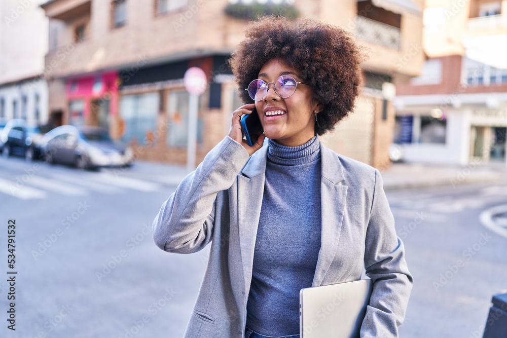 African american woman executive talking on smartphone holding laptop at street African american woman executive talking on smartphone holding laptop at street