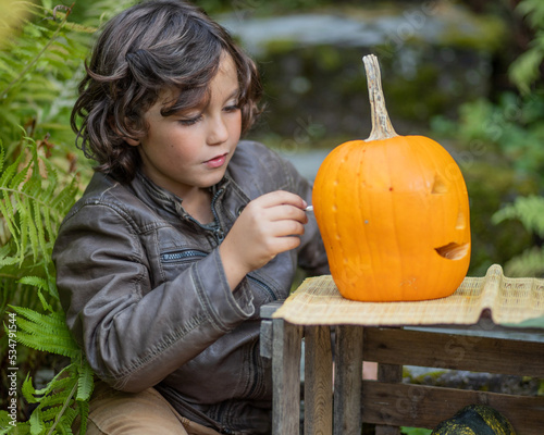 Long-haired brown-eyed boy preparing for Halloween and making a mask, Austria