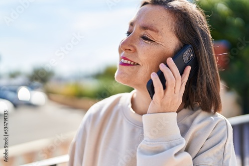 Middle age woman smiling confident talking on the smartphone at park