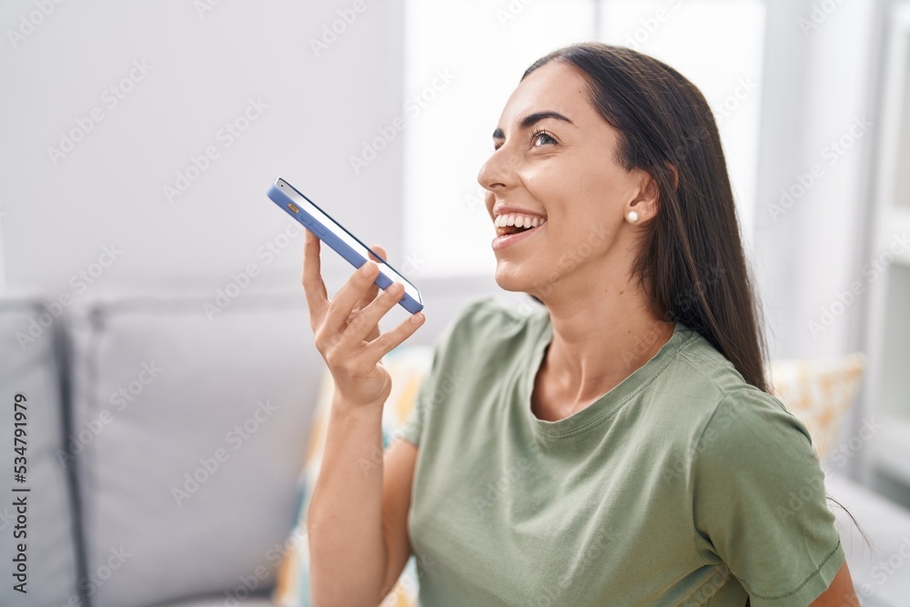Young beautiful hispanic woman talking on smartphone sitting on sofa at home Young beautiful hispanic woman talking on smartphone sitting on sofa at home