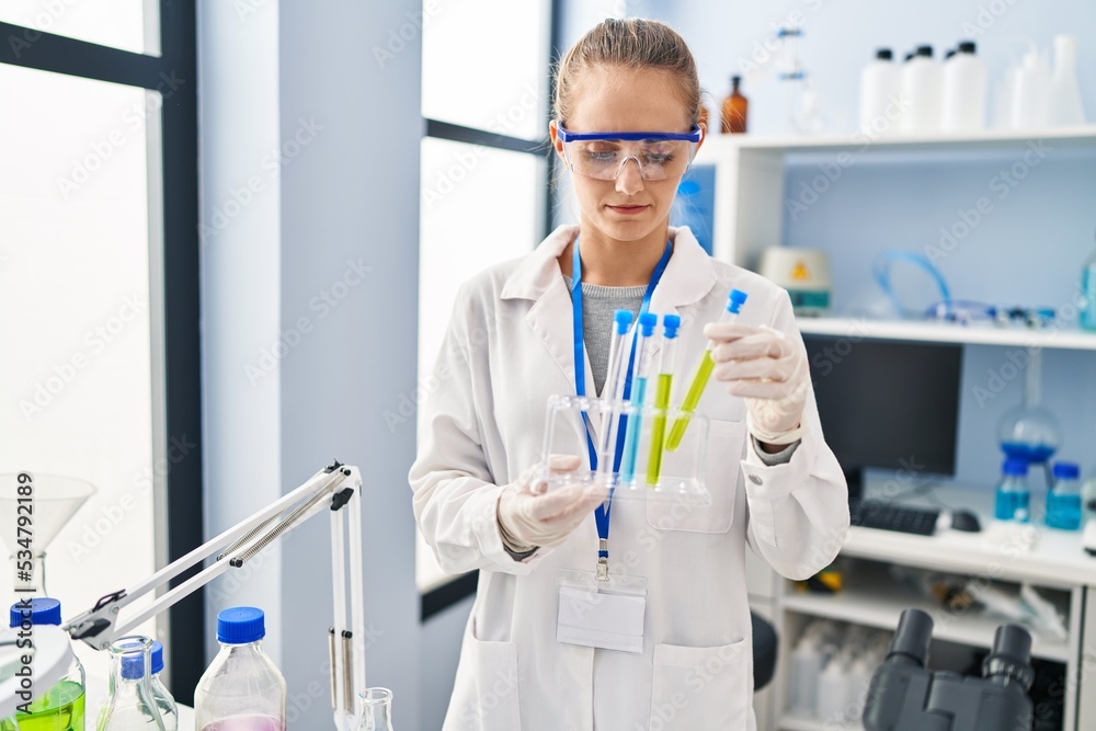 Young blonde woman wearing scientist uniform holding test tube at laboratory Young blonde woman wearing scientist uniform holding test tube at laboratory