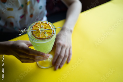 female drinking fresh green cocktail with pisang liquor, orange in bar or cafe photo