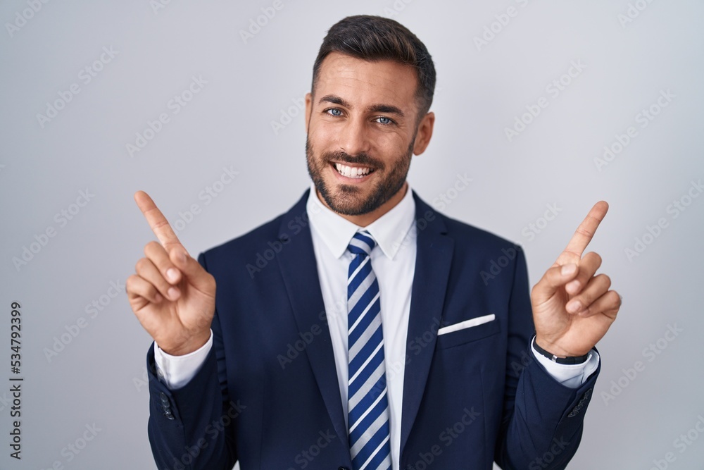 Handsome hispanic man wearing suit and tie smiling confident pointing with fingers to different directions. copy space for advertisement Handsome hispanic man wearing suit and tie smiling confident pointing with fingers to different directions. copy space for advertisement